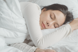 woman asleep in bed with white bedding