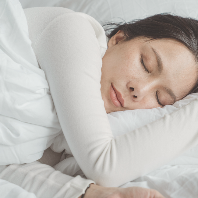 woman asleep in bed with white bedding