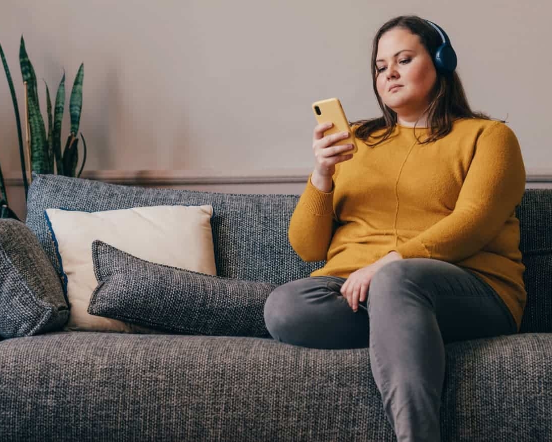 a woman with headphones looking at the besophro app on phone