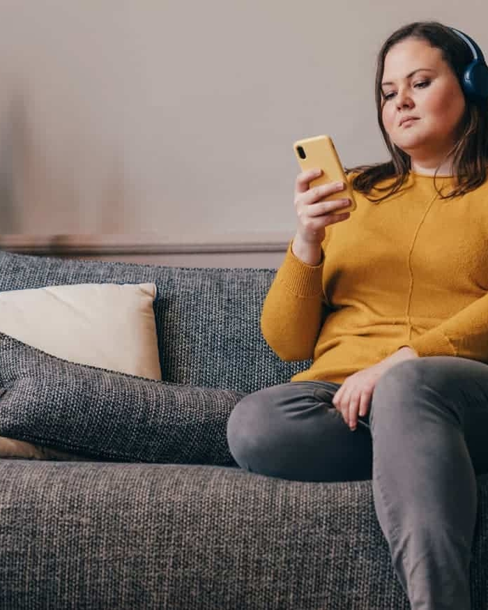 a woman with headphones looking at the besophro app on phone