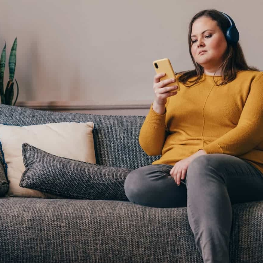 a woman with headphones looking at the besophro app on phone